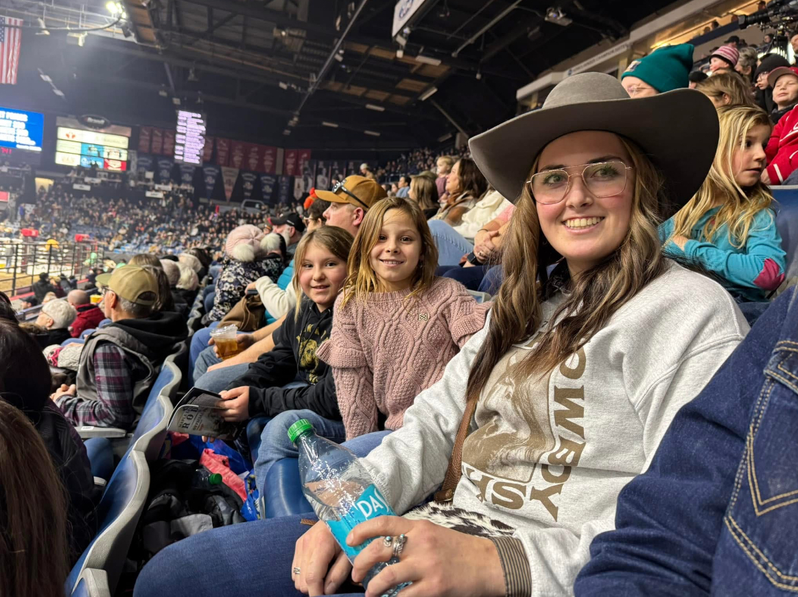 Une femme souriante et deux jeunes enjoués dans les gradins à l’Agribition de Regina.