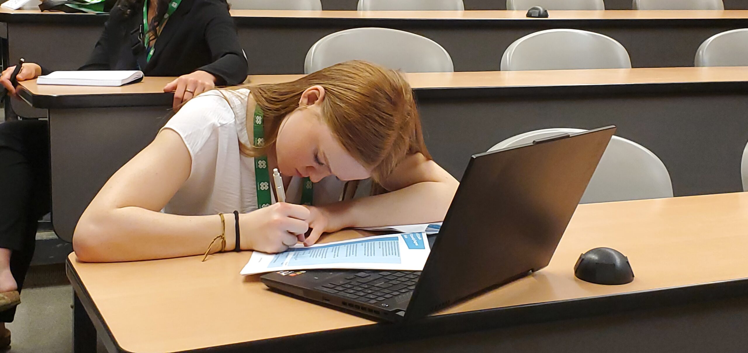 Une jeune femme écrit sur un bout de papier, l’air concentré.