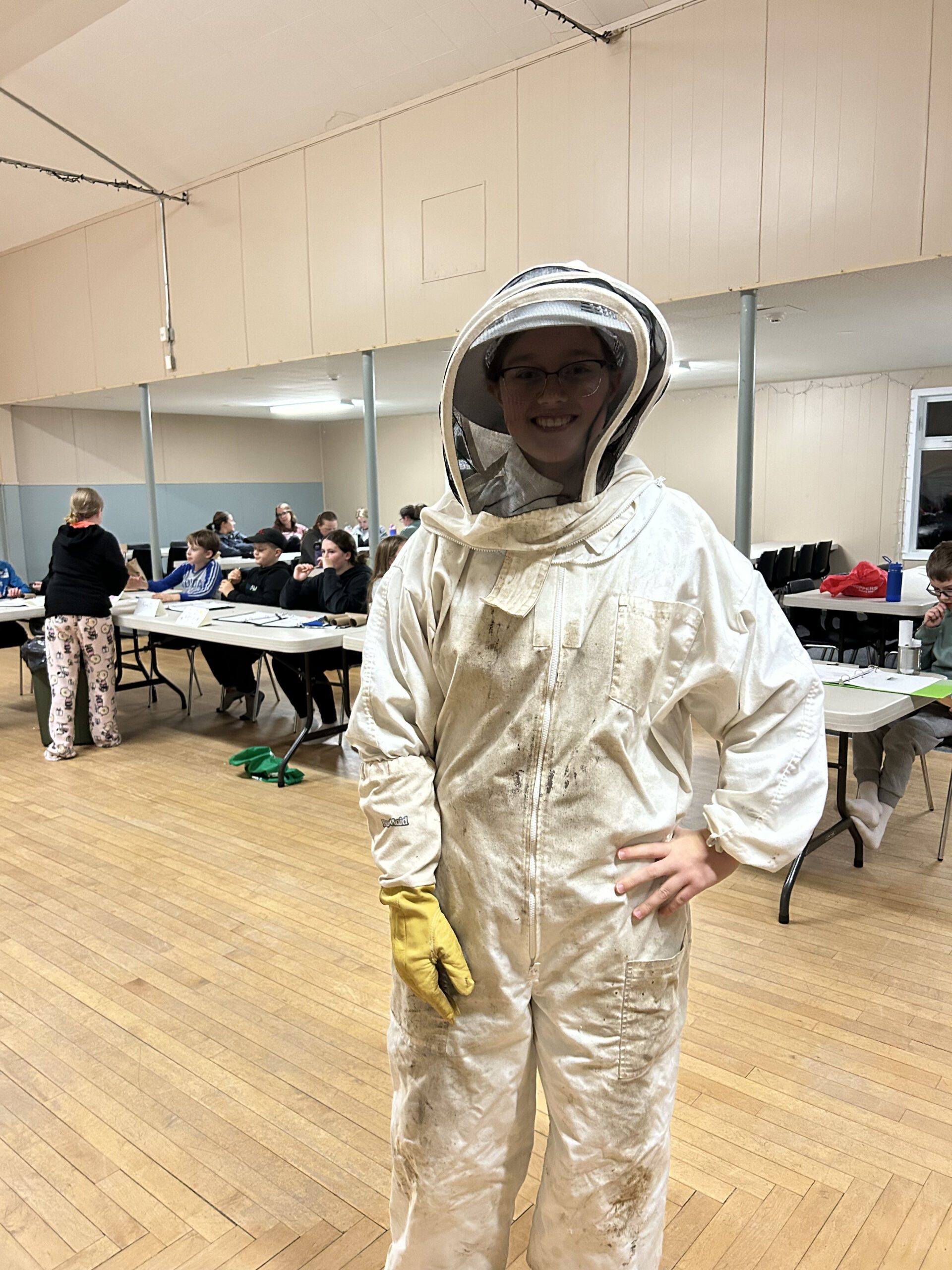 Youth poses for a picture in a beekeeper uniform